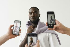 Portrait of a stylish man surrounded by smartphones capturing his image indoors.